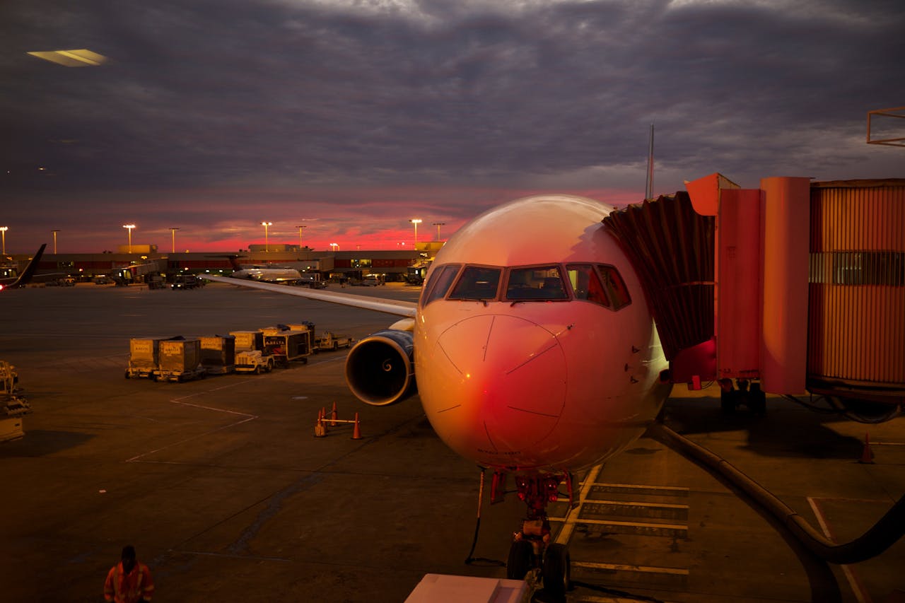 why-choose-me Plane boarding at sunset with vibrant sky colors and airport lights.