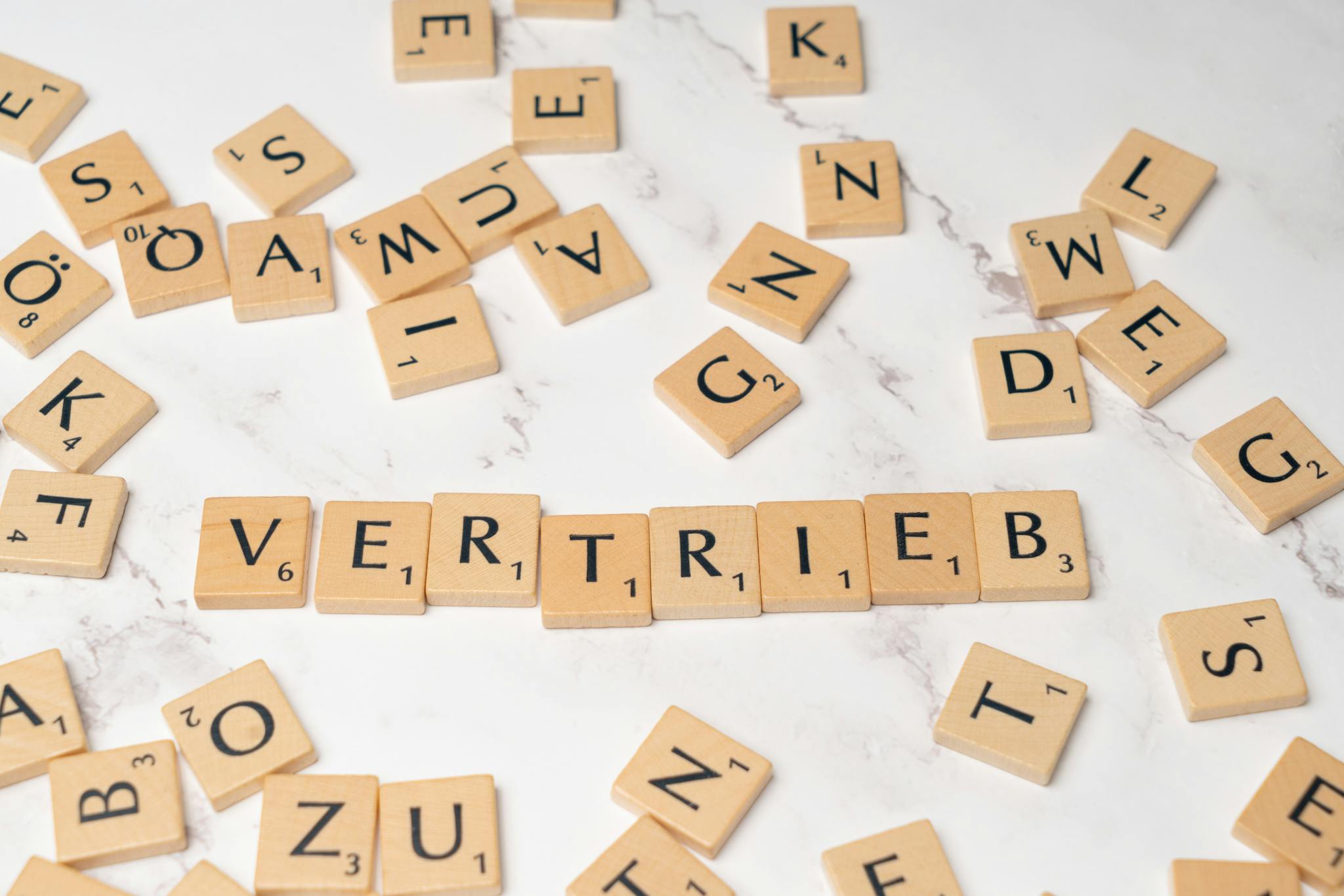 Scrabble tiles arranged to spell 'Vertrieb' on a marble surface, symbolizing sales.